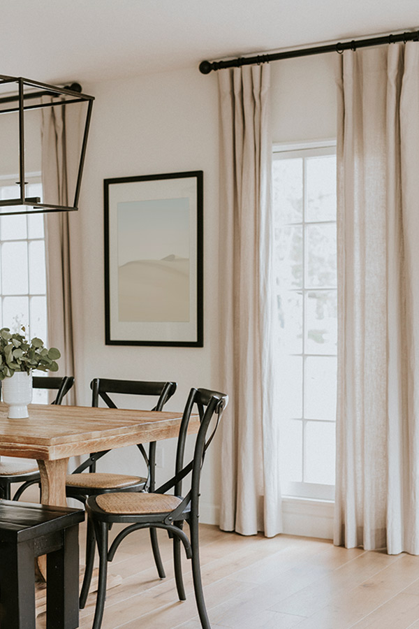 Neutral modern and transitional interior design of a dining table and window treatments by Andi Felitz of Bevel Design & Interiors.