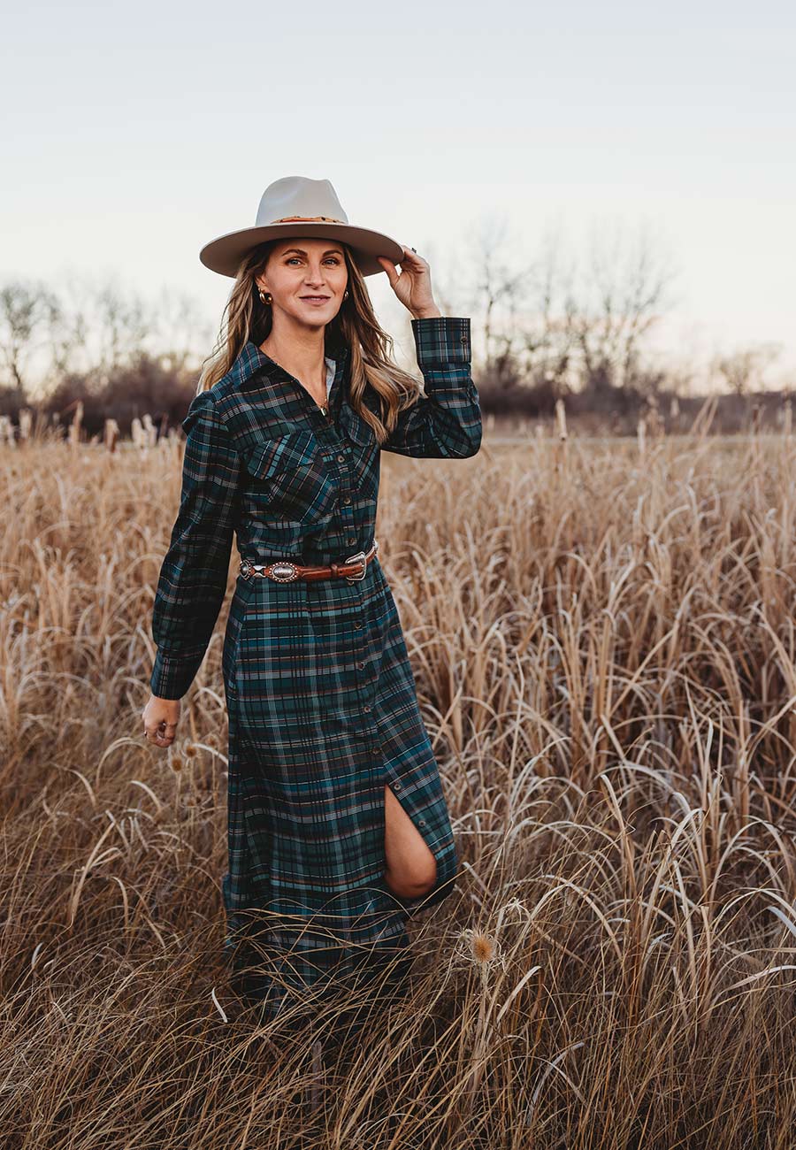Andrea Felitz owner and designer of Bevel Design & Interiors stands in front of a fence in a clean modern outfit. 